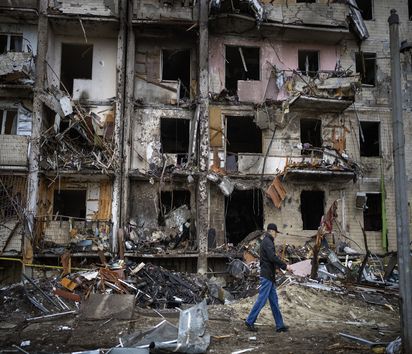 Ein Mann geht vor einem von russischen Raketen zerstörten Gebäude in Kiew vorbei.