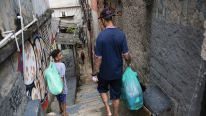 Vinnicius Fragoso (26) Koordinator des Projektes Futebol de Rua, begleitet Thaylor Pietro Souza Santos (12) nach Hause, Sapopemba, Sao Paulo, Brasilien