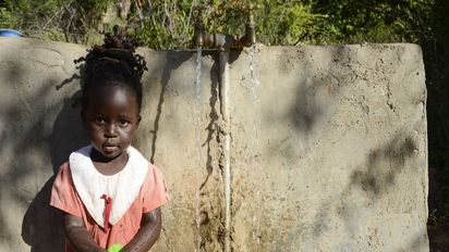 Mädchen in Kenia an einer Wasserstelle beim Abfüllen von Kanistern.