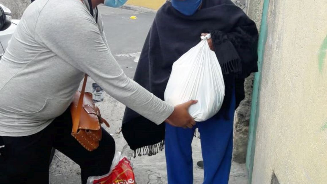 Übergabe eines Lebensmittelpaketes durch eine Mitarbeiterin von INREDH