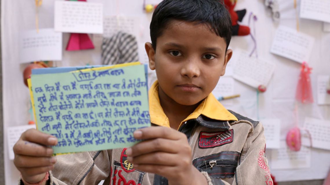 Ein Junge hält eine beschriftete grüne Karteikare in die Kamera