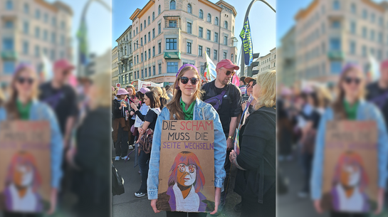 "Die Scham muss die Seiten wechseln!" Demo-Teilnehmerin mit Plakat mit Konterfei von Gisele Pelicot und der Aufschrift "Die Scham muss die Seiten wechseln!"