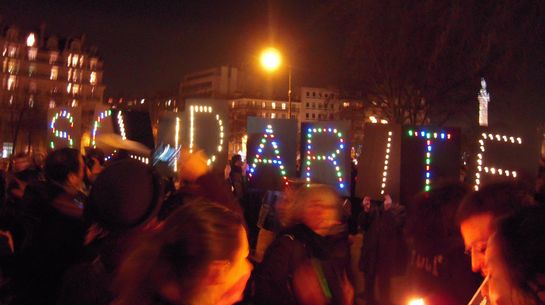 Menschen auf einer Demonstration halten den beleuchteten Schriftzug SOLIDARITE hoch.