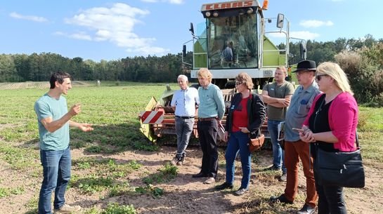 Auf dem Feld tauschen sich die Beteiligte aus, Traktor im Hintergrund