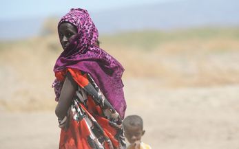 Frau mit kleinem Kind vor Savannenlandschaft