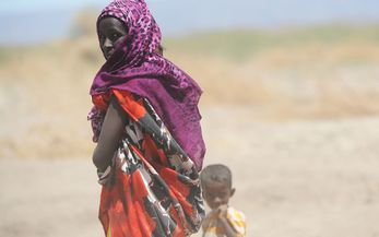 Frau mit kleinem Kind vor Savannenlandschaft