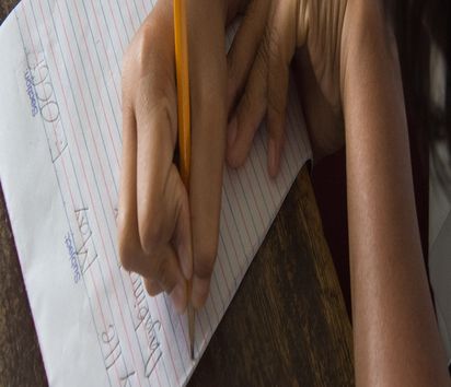 Kind schreibt etwas auf einen Schreibblock