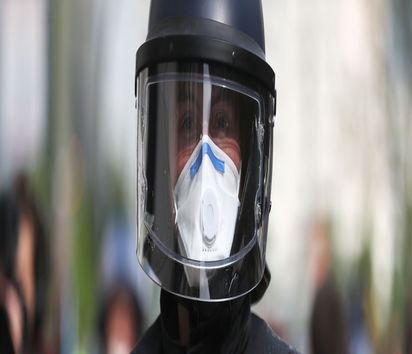 Ein Polizist mit Mundschutz und Einweghandschuhe in Schutzkleidung.