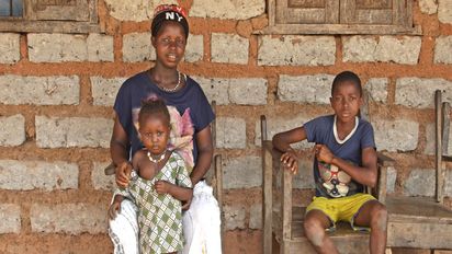 Hawa Conteh sitzt in Sierra Leone mit ihrer Familie vor ihrem Haus.