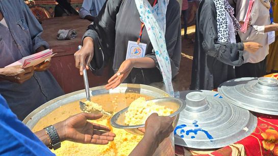 Suppenküche im Sudan Frau schöpft Getreidebrei aus einem großen Topf